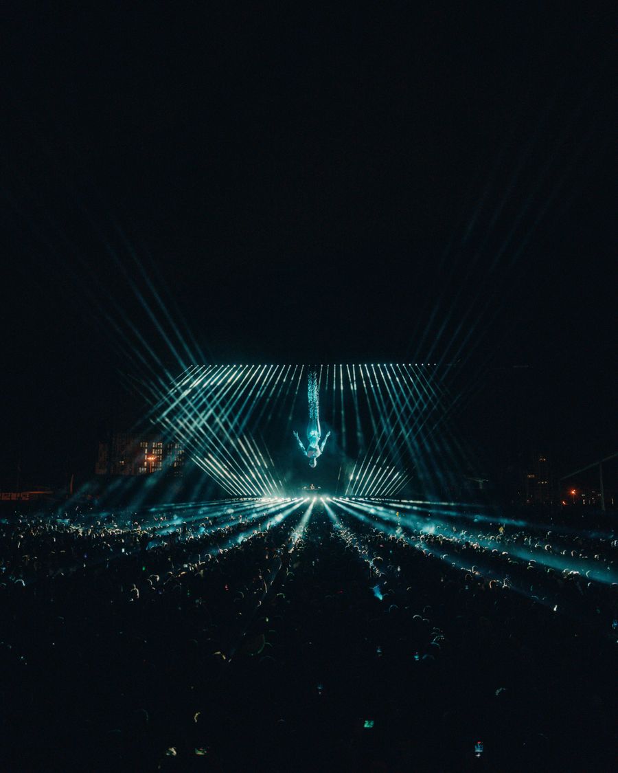 Festival main stage glowing teal against the night sky