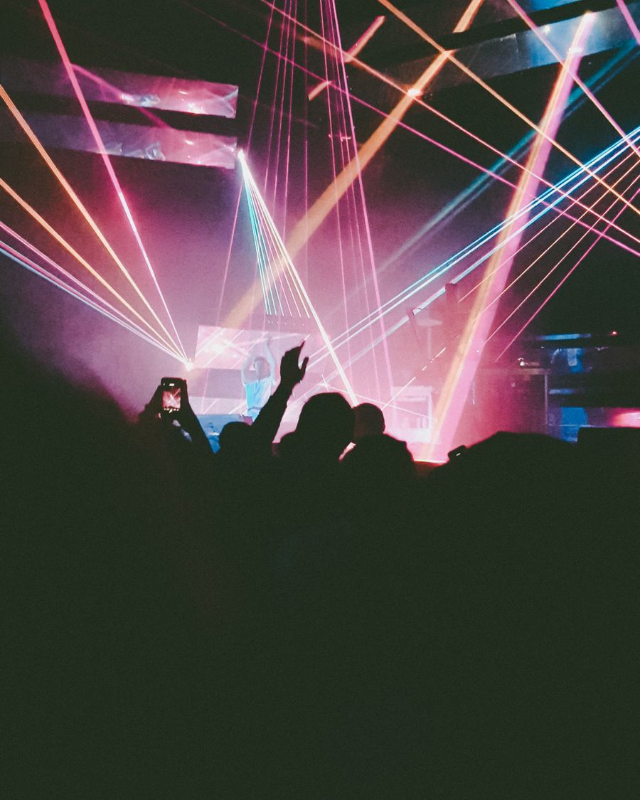 Arena crowd silhouetted under pink laser lights