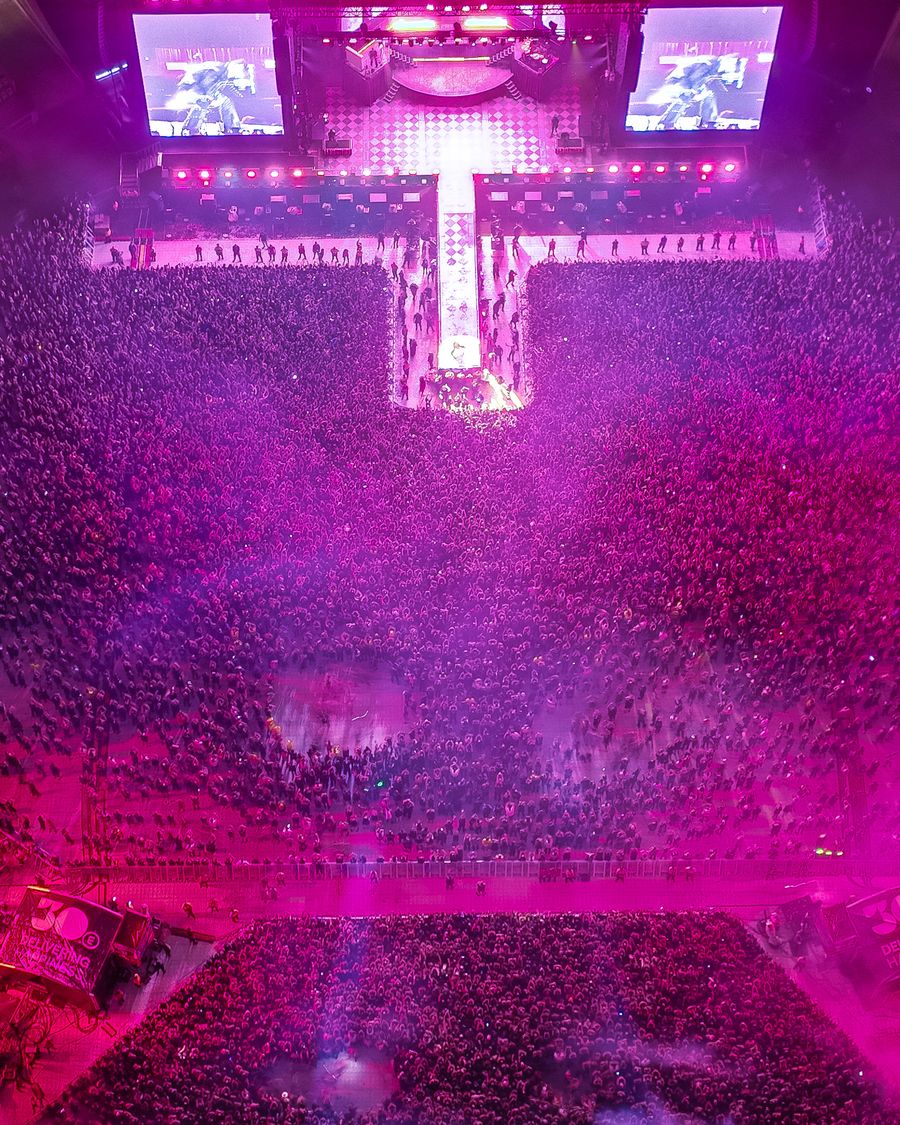 Stadium concert seen from above, stage bathed in purple light