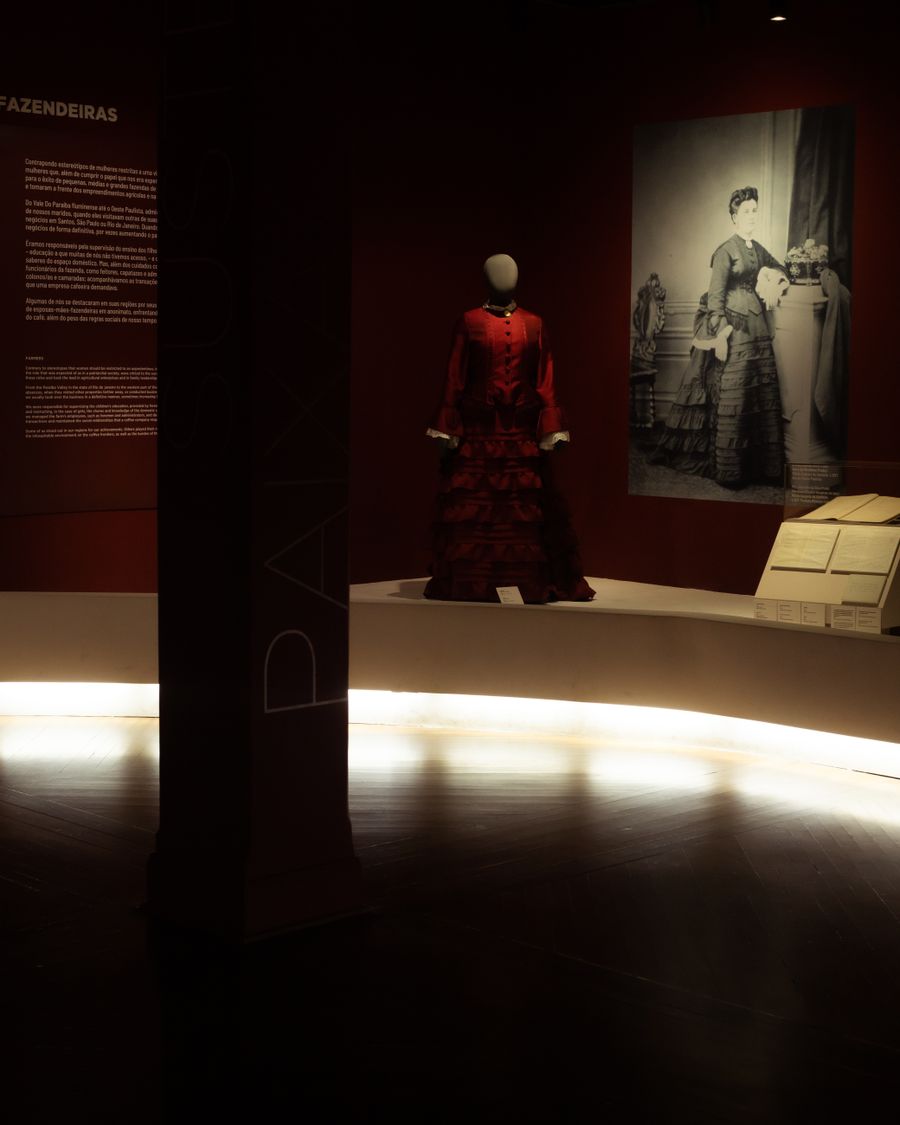 Couture dresses displayed in a dimly lit museum gallery
