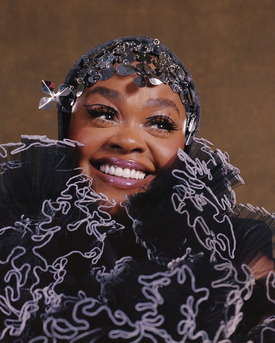 Jill Scott smiling in a sculpted black top and jewelled headpiece - the official tour image