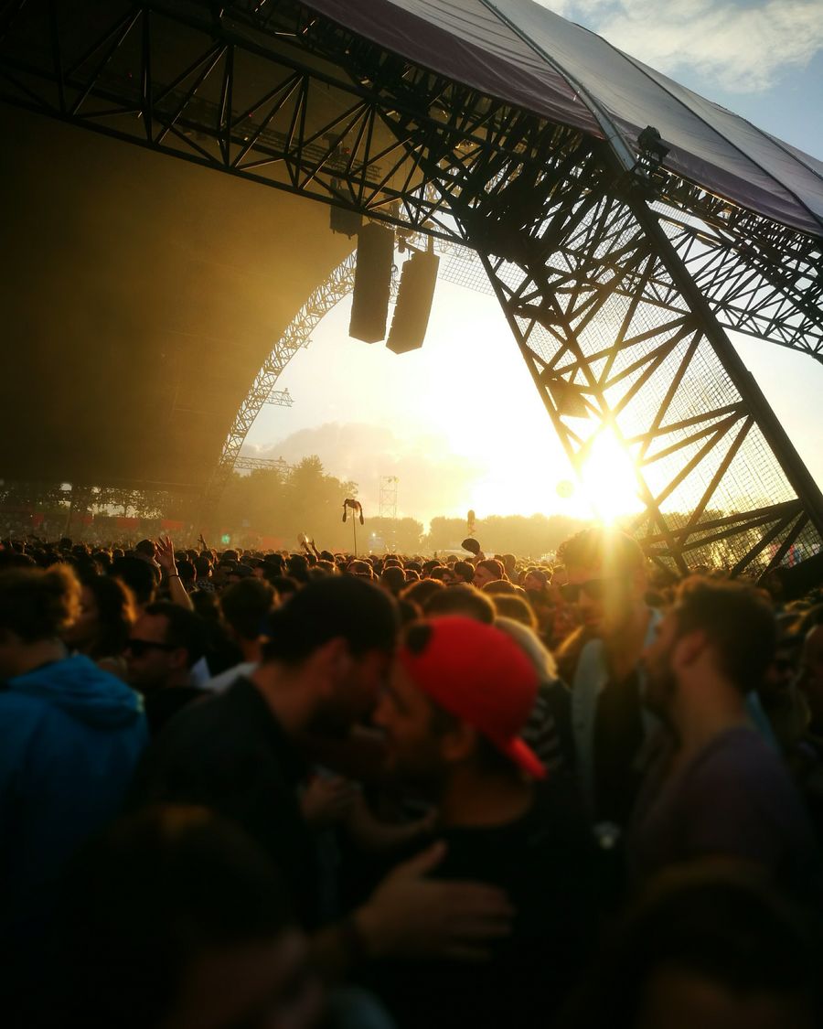 Festival crowd under a stage structure at sunset