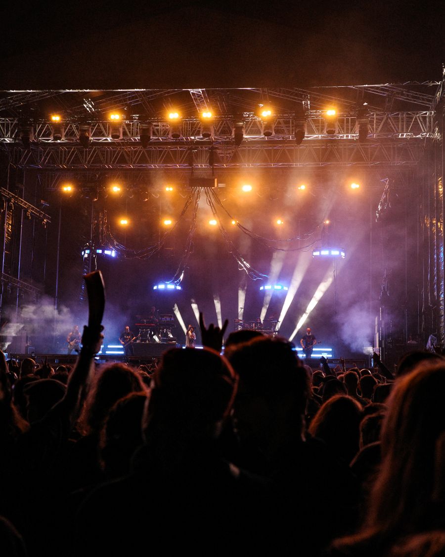 Open-air stage rig glowing amber over an evening crowd
