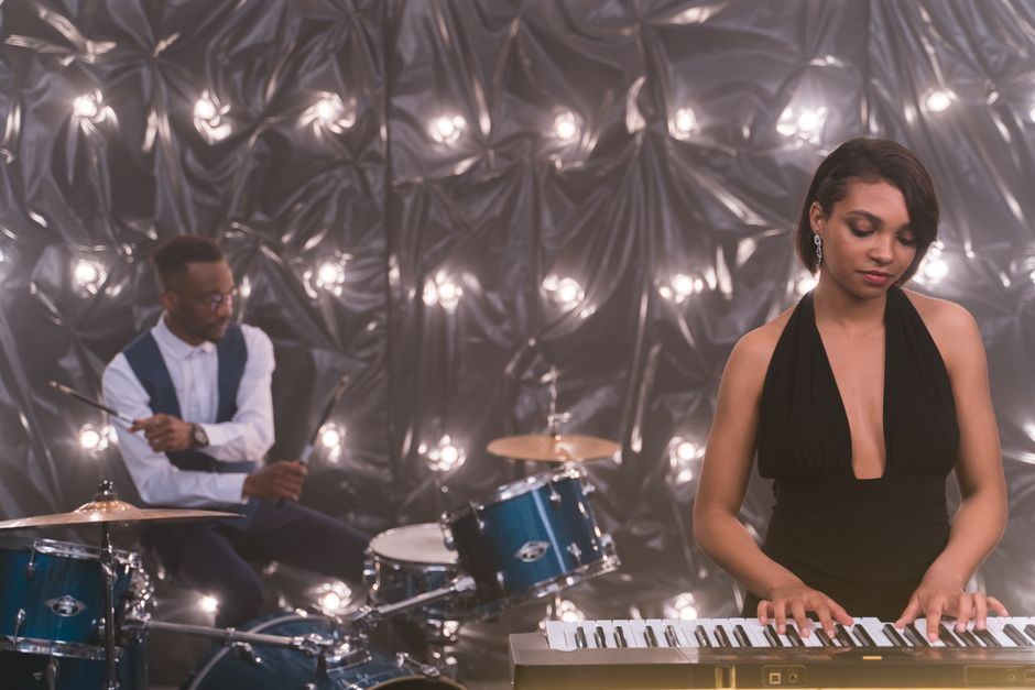 Two musicians performing piano and double bass under string lights