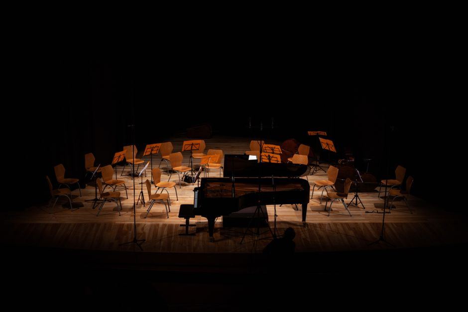 A chamber orchestra seated on a dark concert stage - classical recital staging