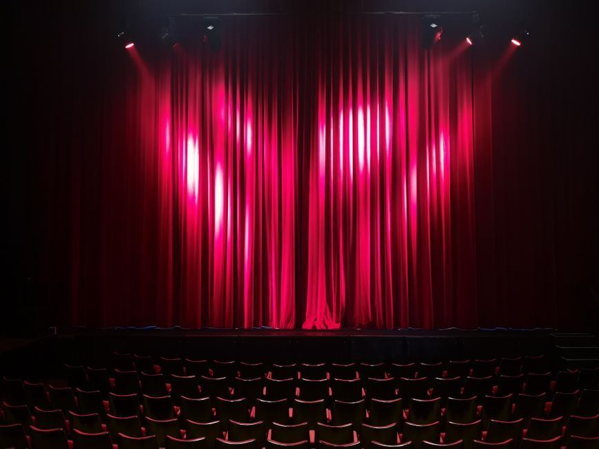 Red velvet theatre curtain and empty seating - a stage-set image for Angels in America