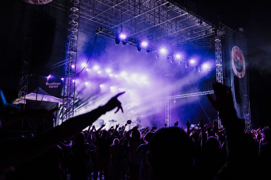 A concert crowd facing a purple-lit stage