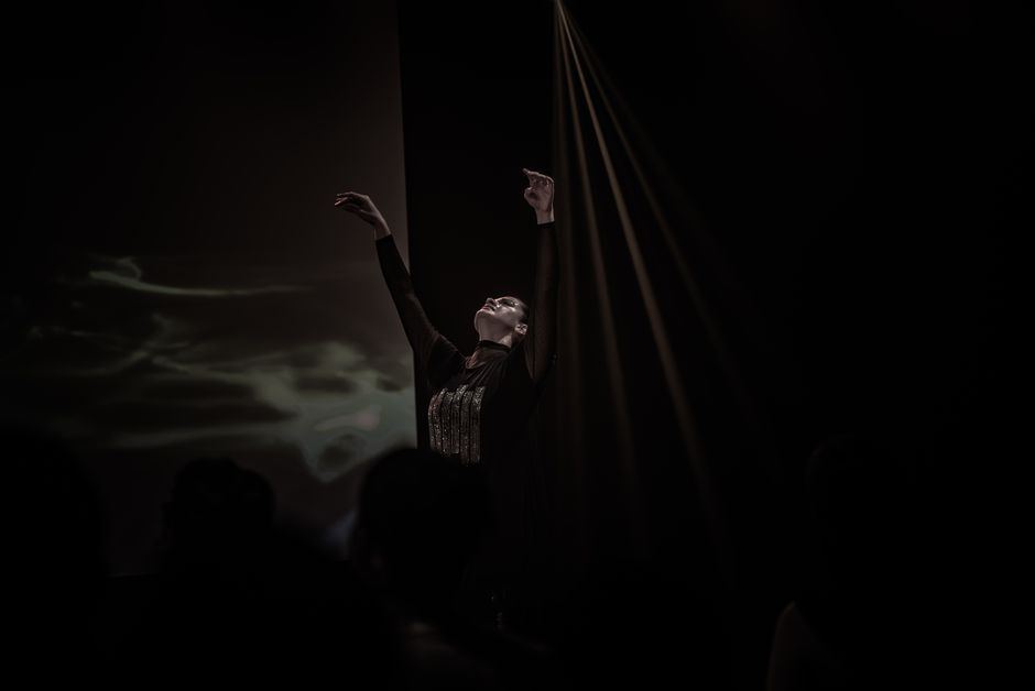 A solo performer under dramatic stage lighting and drifting smoke