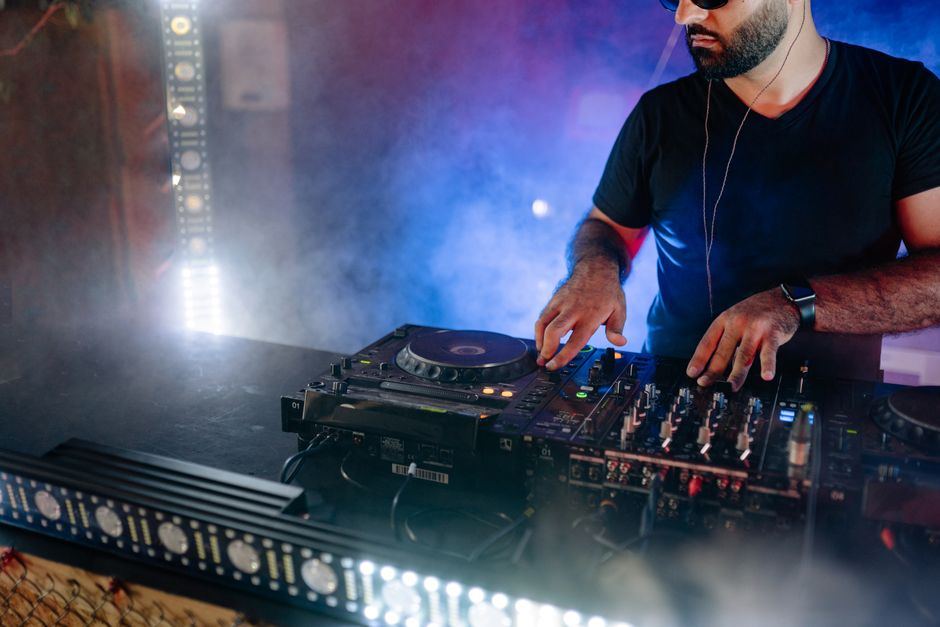 A DJ performing at turntables under blue stage lighting