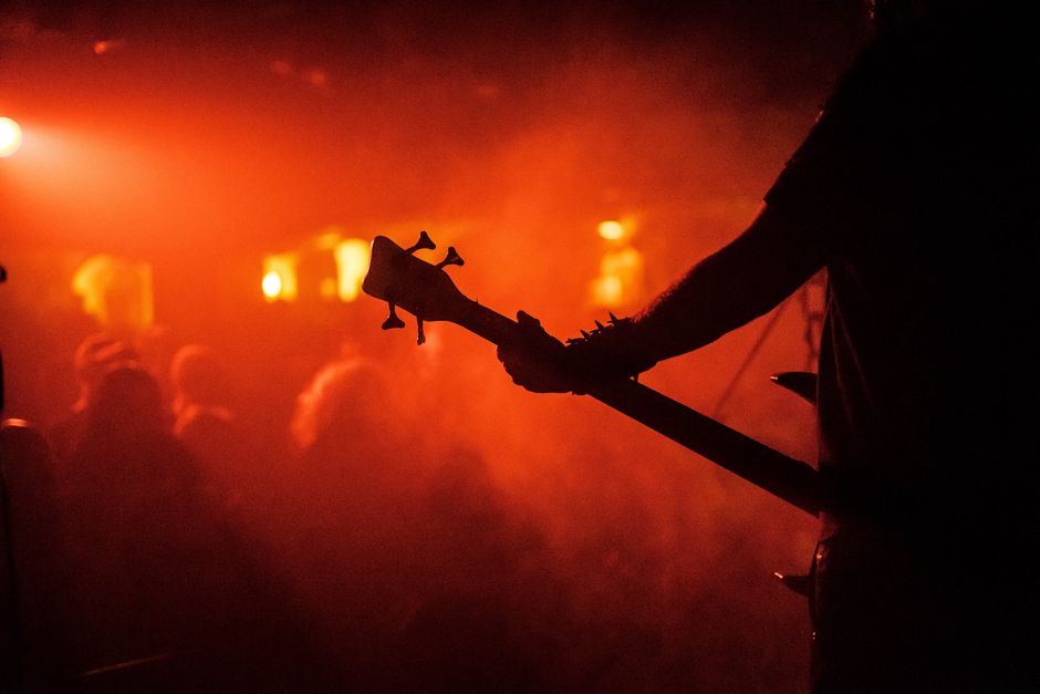A hand reaching up under dramatic red and orange stage lighting