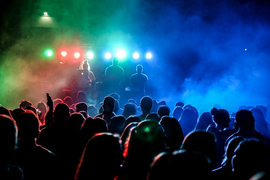 A crowd under colourful stage lighting at a club night