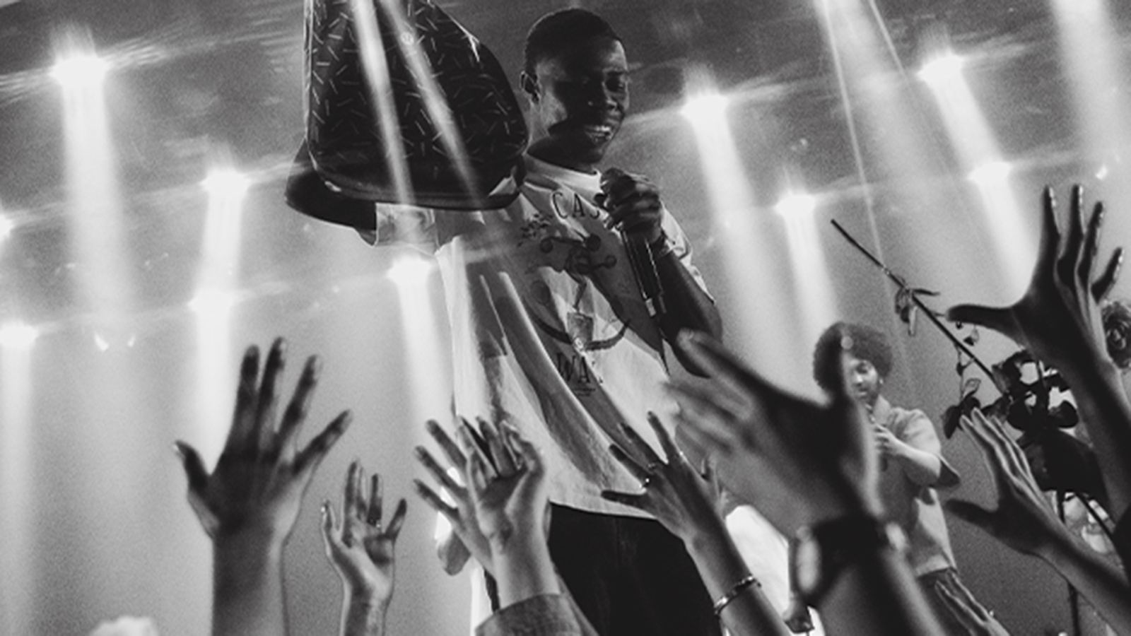 A black-and-white crowd with hands raised at a club night