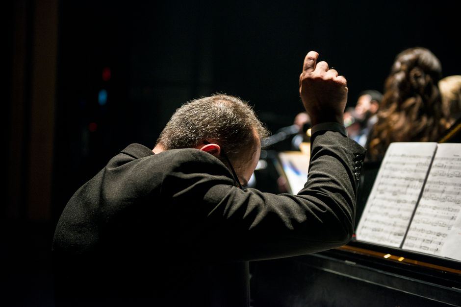 A conductor mid-gesture leading an orchestra