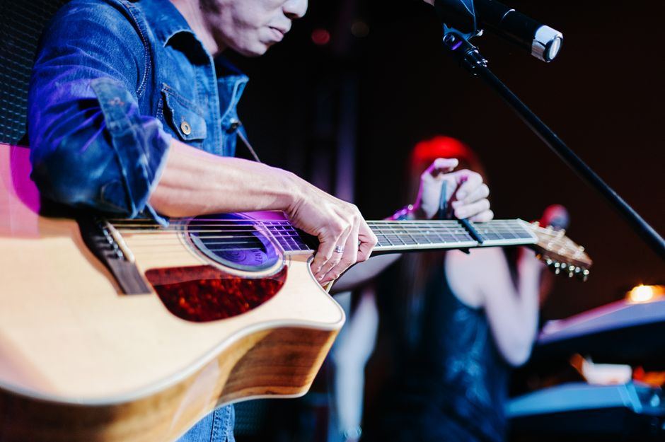 A musician playing acoustic guitar in a red cap