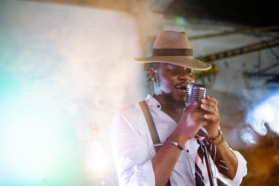 A jazz vocalist in a hat singing under warm stage light