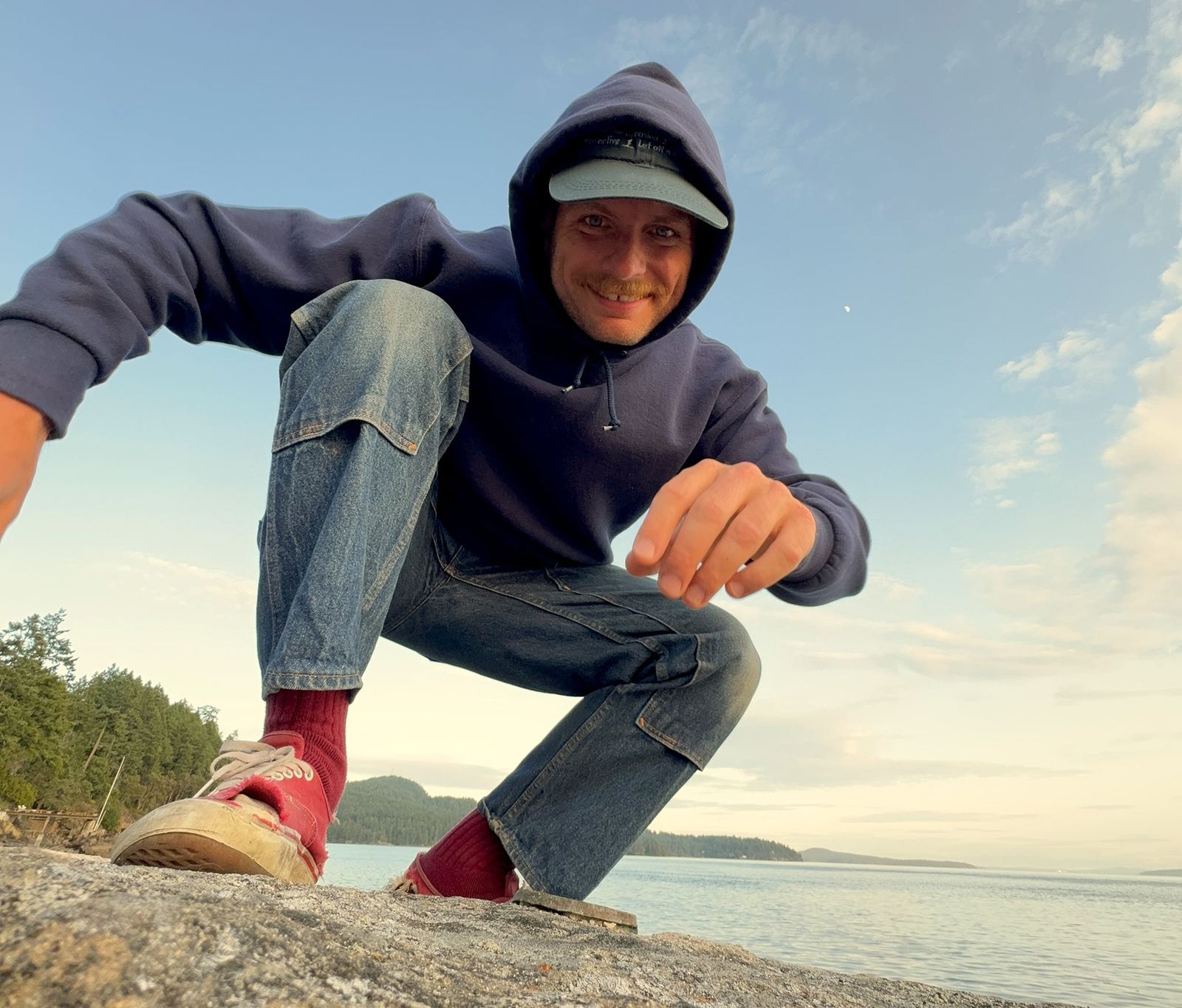 Mac DeMarco crouching outdoors in a promotional portrait