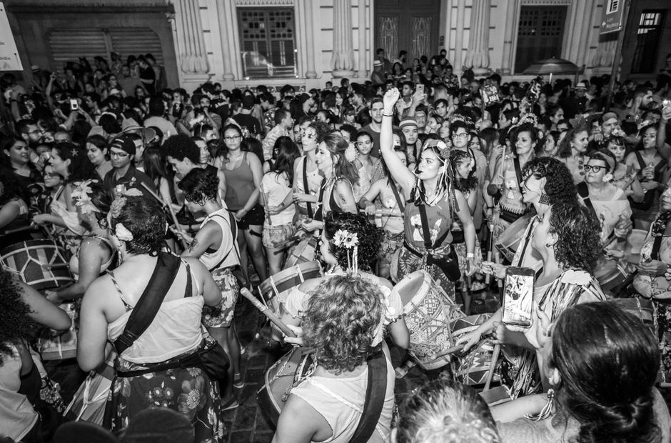 A packed crowd with hands raised at a baile funk night