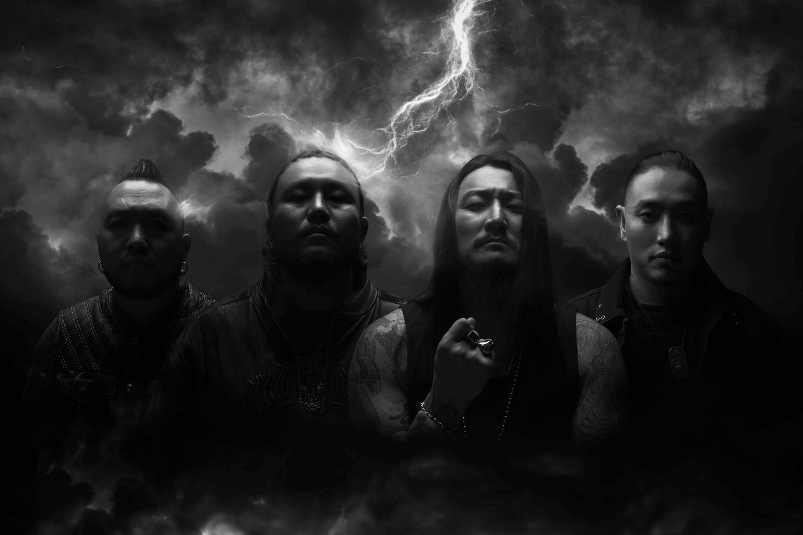 The four members of The Hu in black and white under storm clouds and lightning, the official band photo