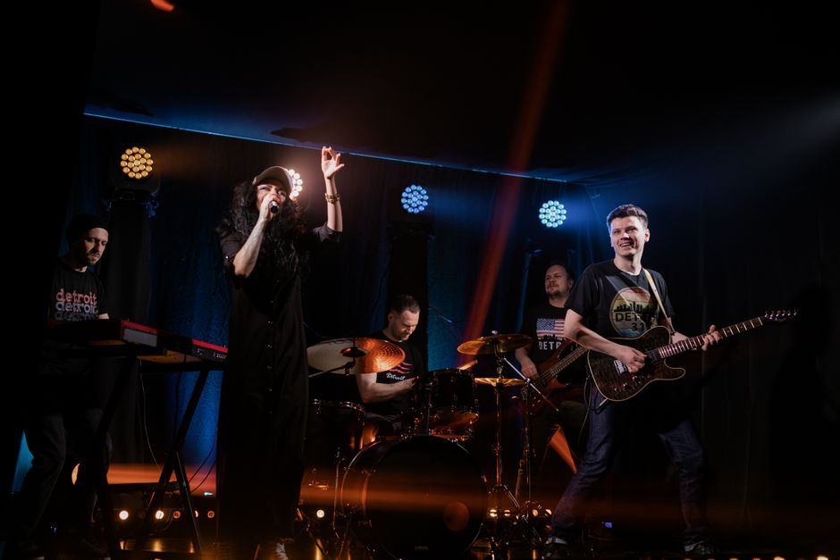 A folk-rock band performing live on stage under warm lighting
